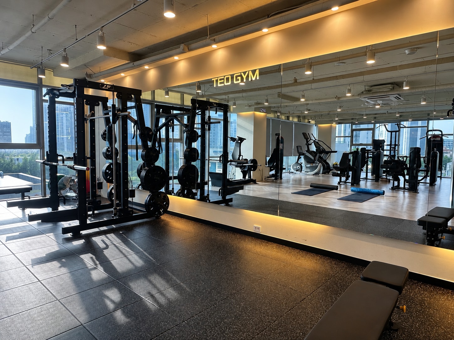 테오짐 PT 청라점 스튜디오 - TEO GYM 로고 거울과 스미스머신 프리웨이트 존, 통창 너머 청라 전망